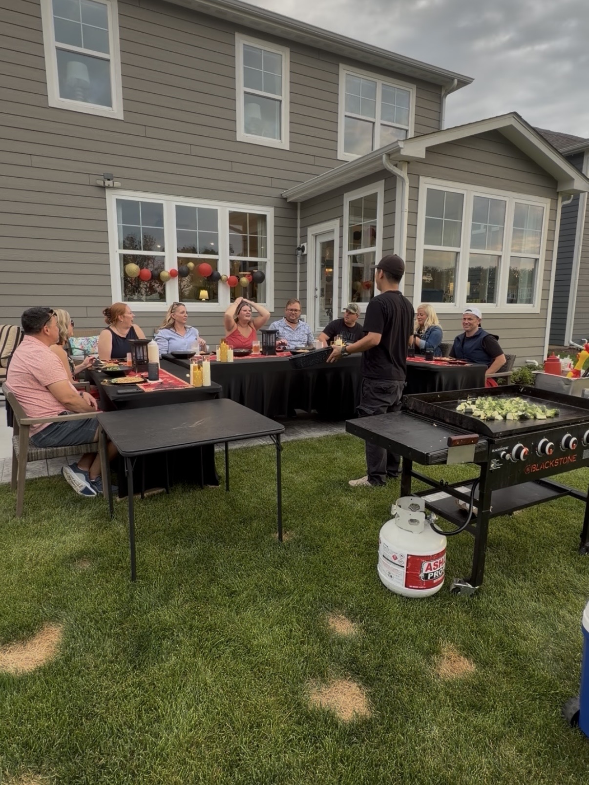 Guests gathered around a backyard hibachi dinner